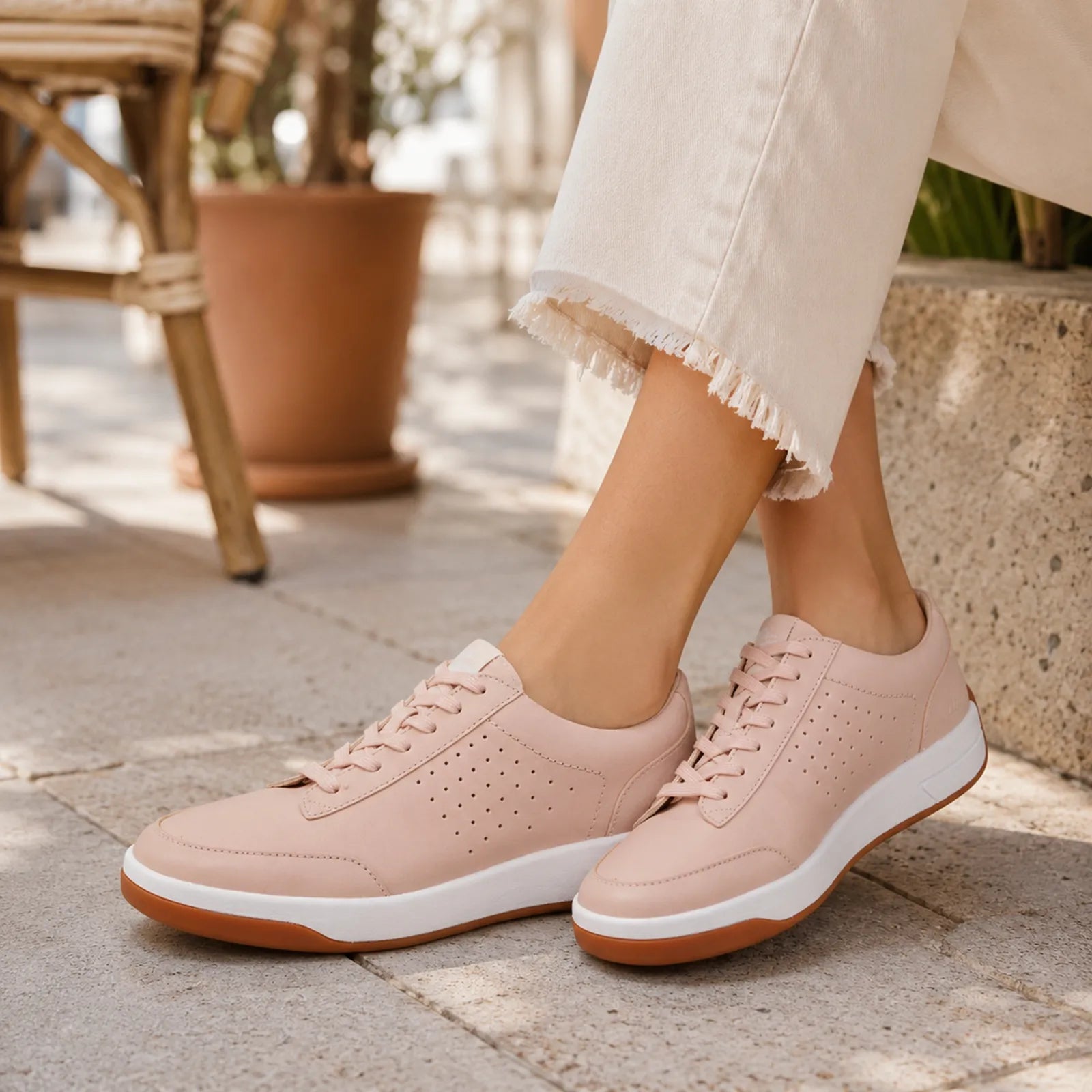Pink leather lace-up sneakers with perforated details and white sole, angled side view