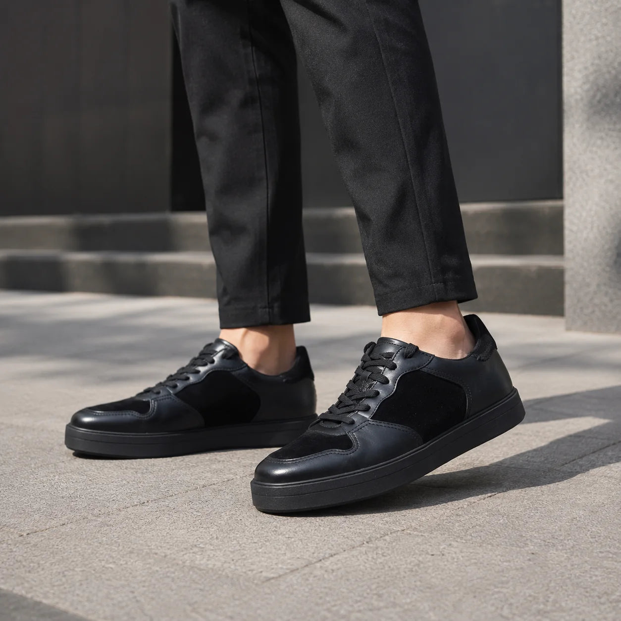 Men's black leather lace-up sneakers on feet with rubber sole