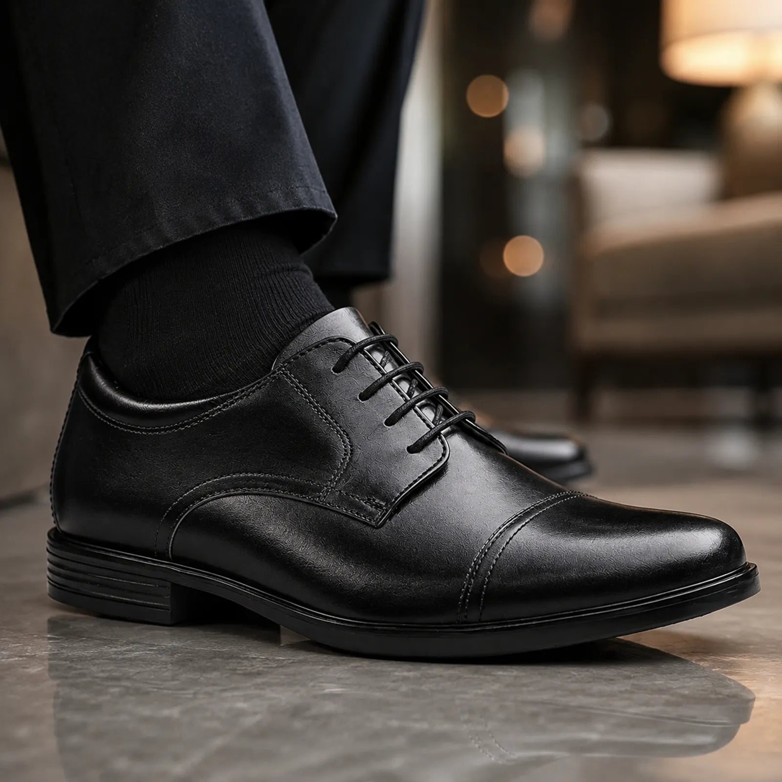 Men's black leather lace-up shoe close-up, cap-toe with stitched panels