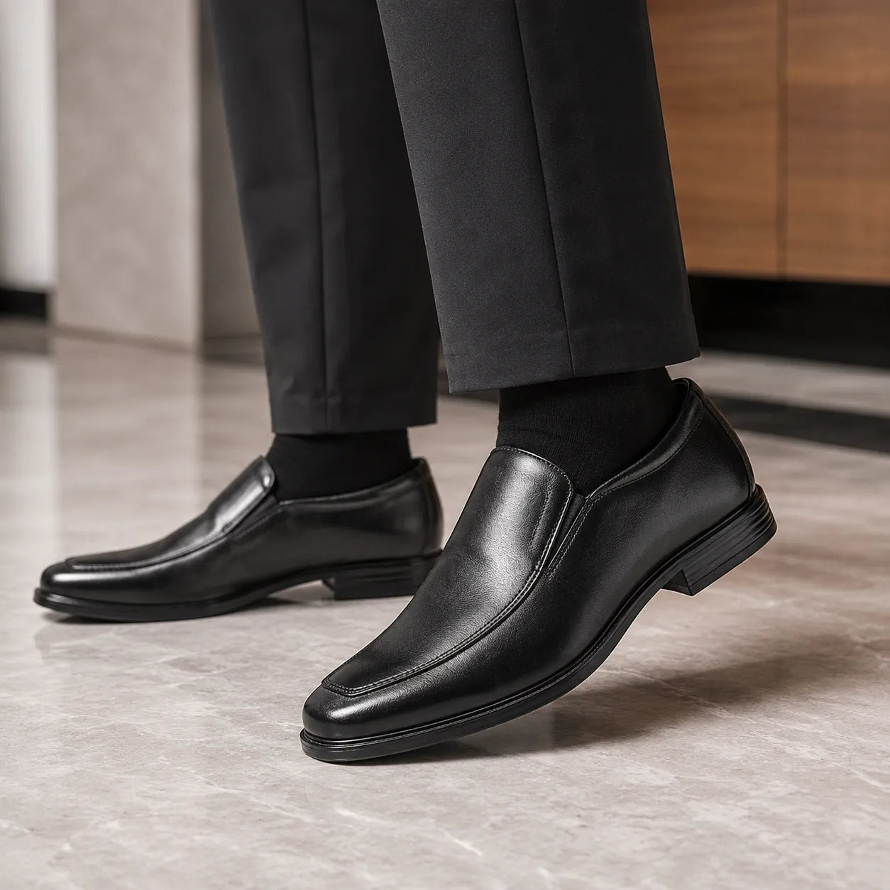 Black leather slip-on shoes shown with trouser pant cuffs