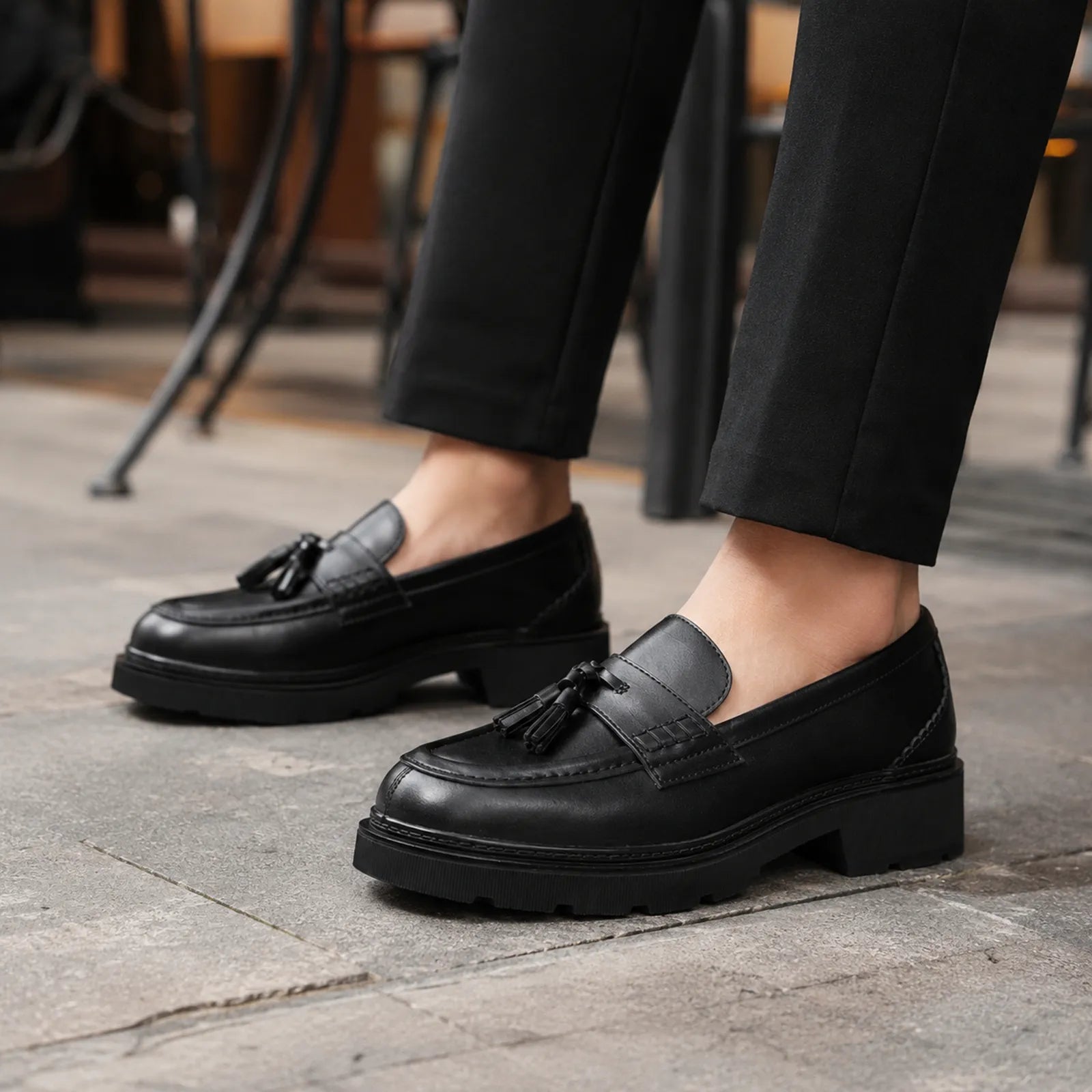 Close-up of women's black leather tassel loafers on pavement
