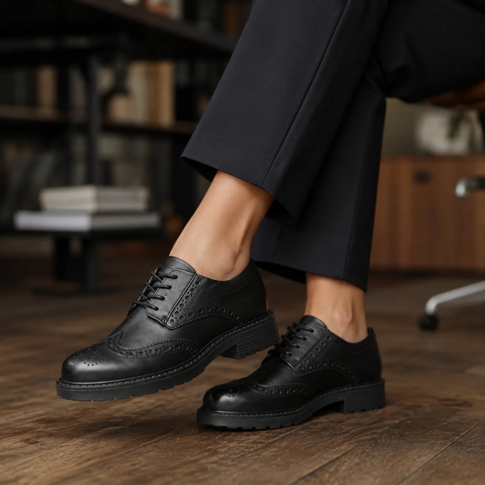 Black leather brogue lace-up shoes with stacked sole, worn with dark trousers.