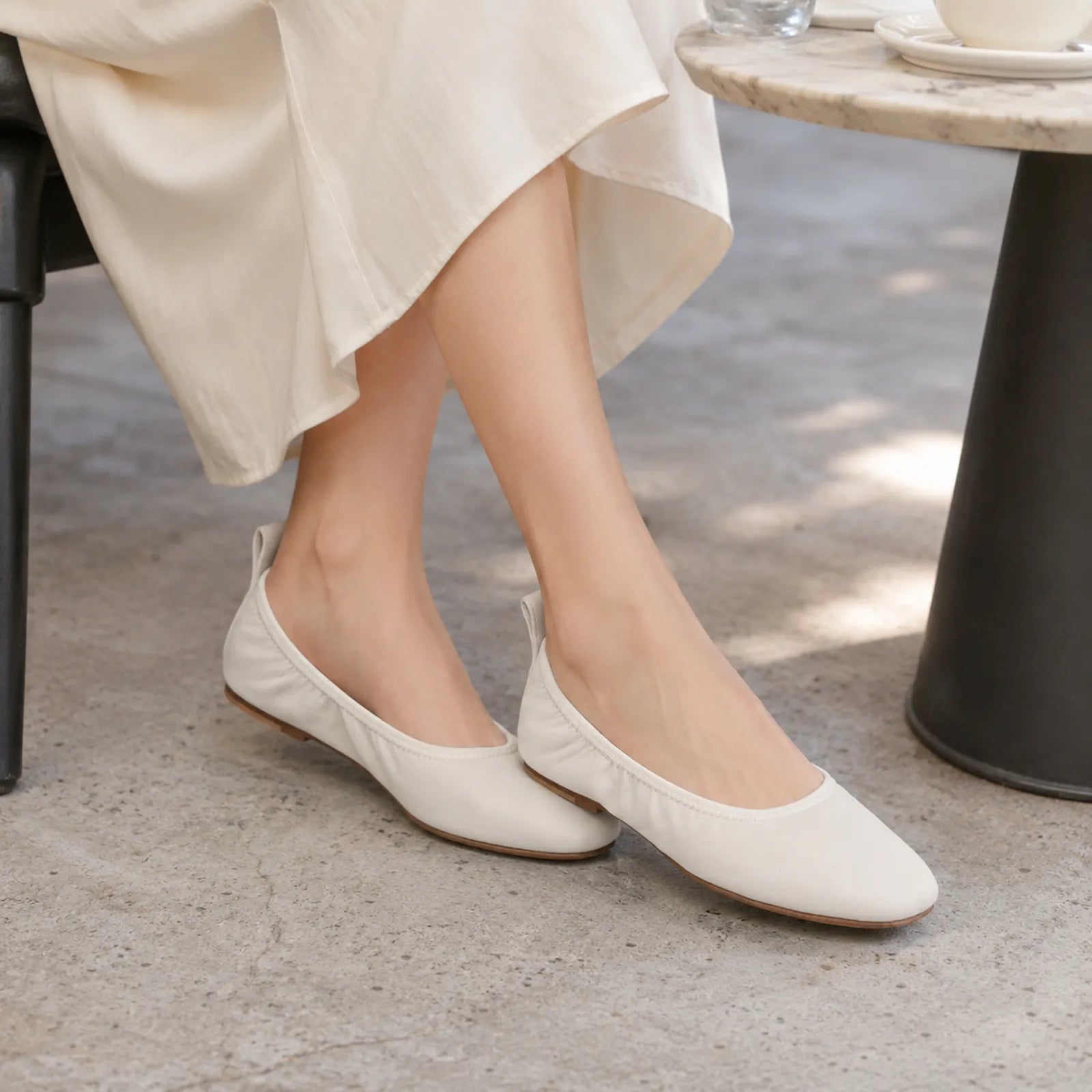 White ballet flats worn with cropped pants, rounded toe and low sole