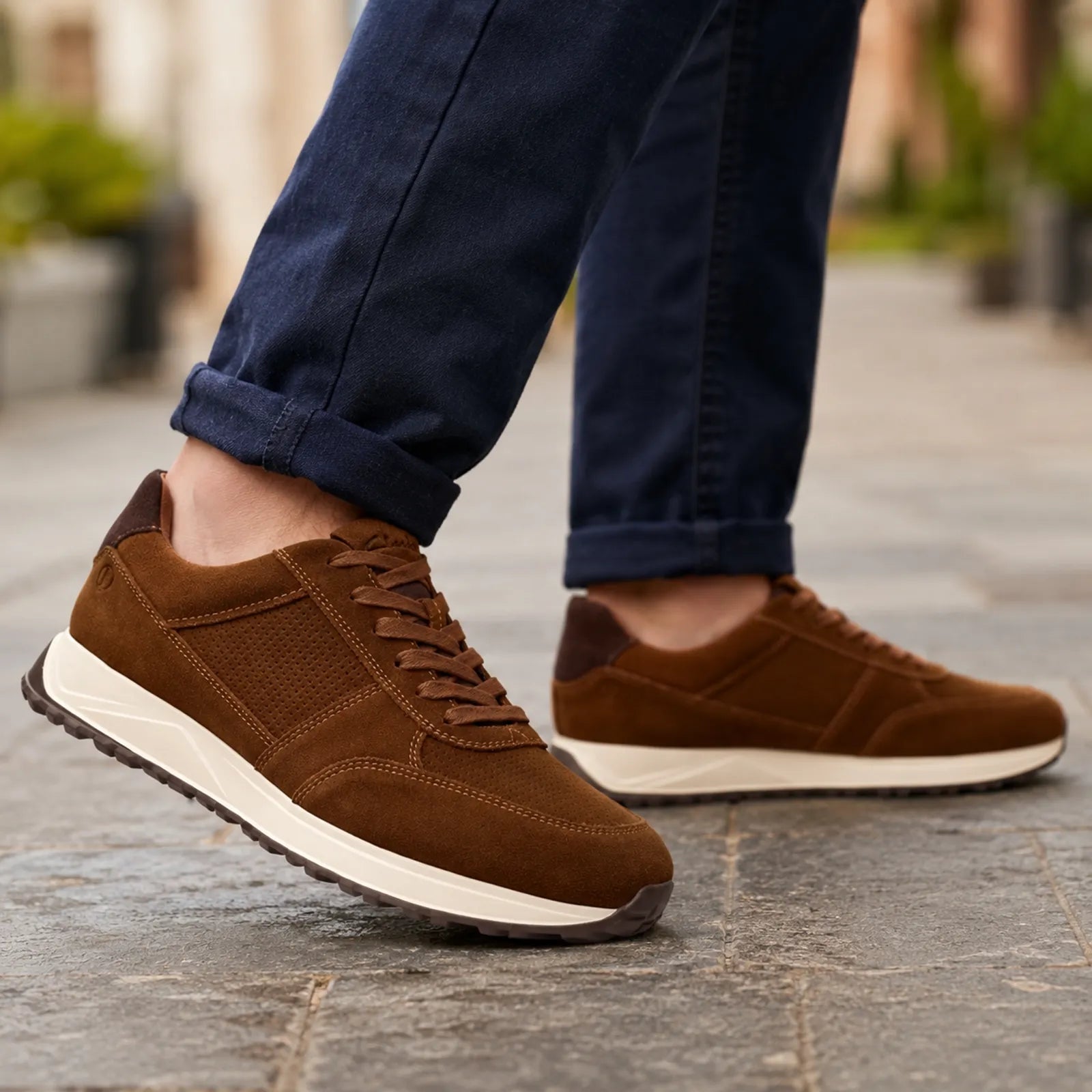 Men's brown lace-up sneakers with white midsole, worn on outdoor pavement