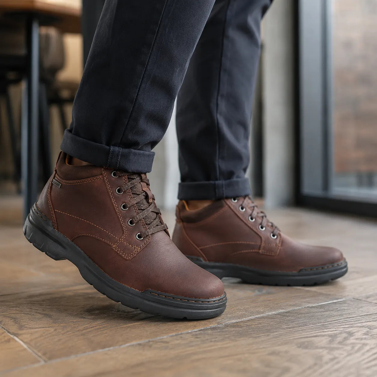 Men's brown leather lace-up boots on feet with thick dark tread sole