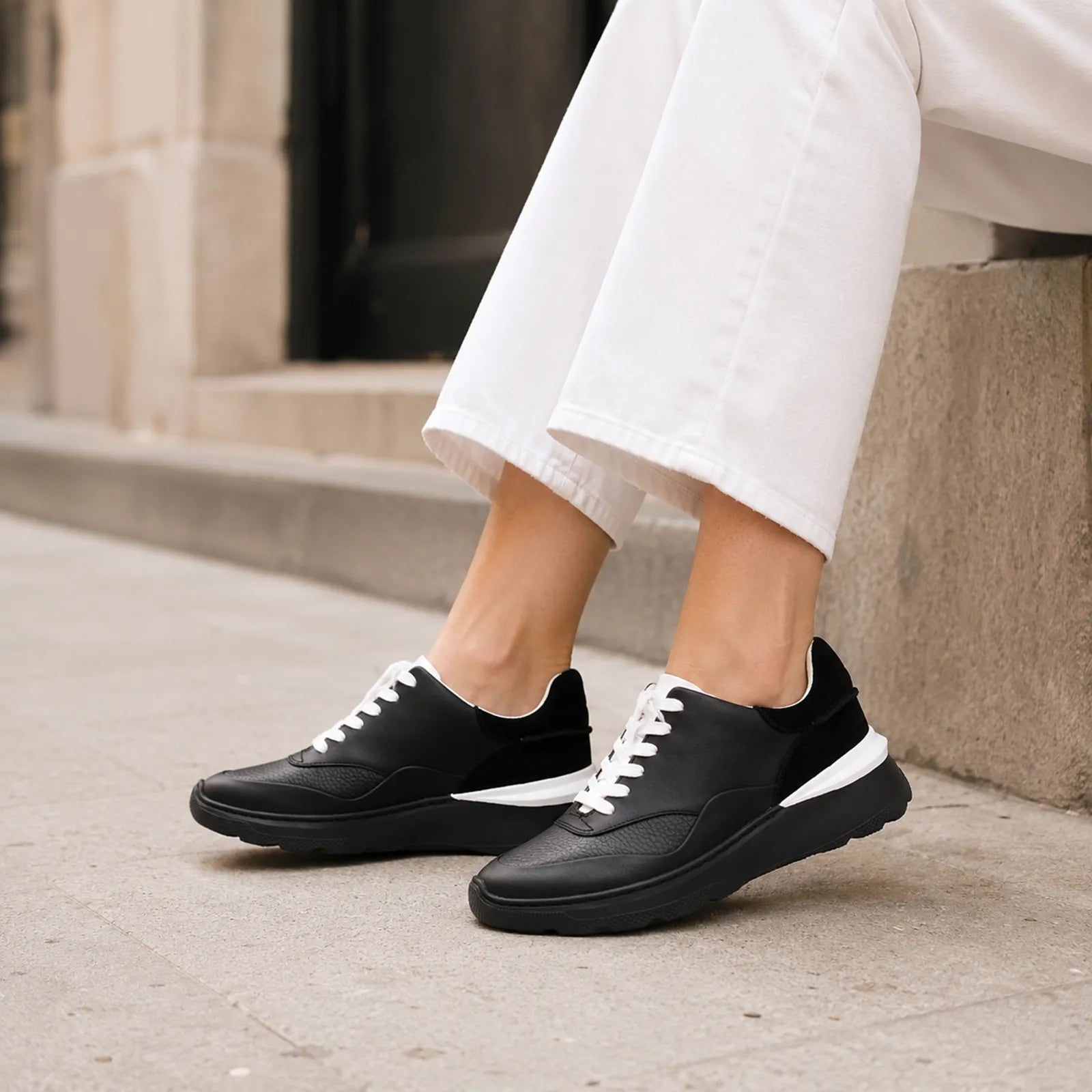 Women's black leather sneakers with white lace-up front and thick cushioned sole