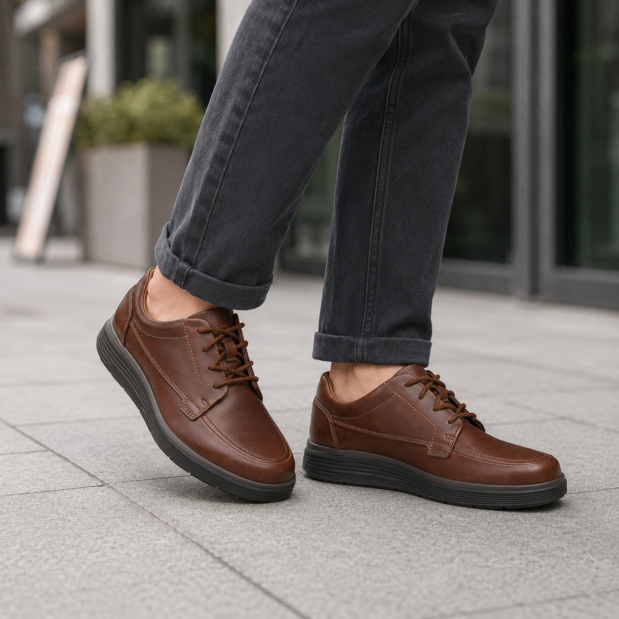 Brown leather lace-up business shoes worn with jeans, featuring a cushioned sole