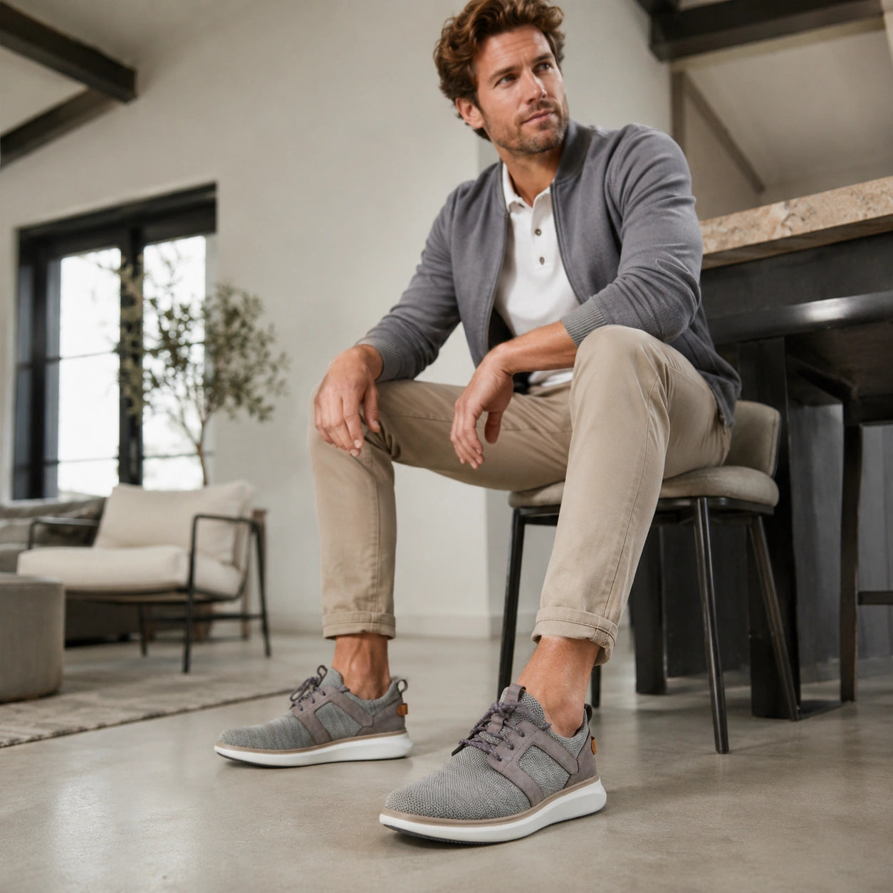 Men's grey lace-up sneakers worn with light pants, white sole and dark lace accents