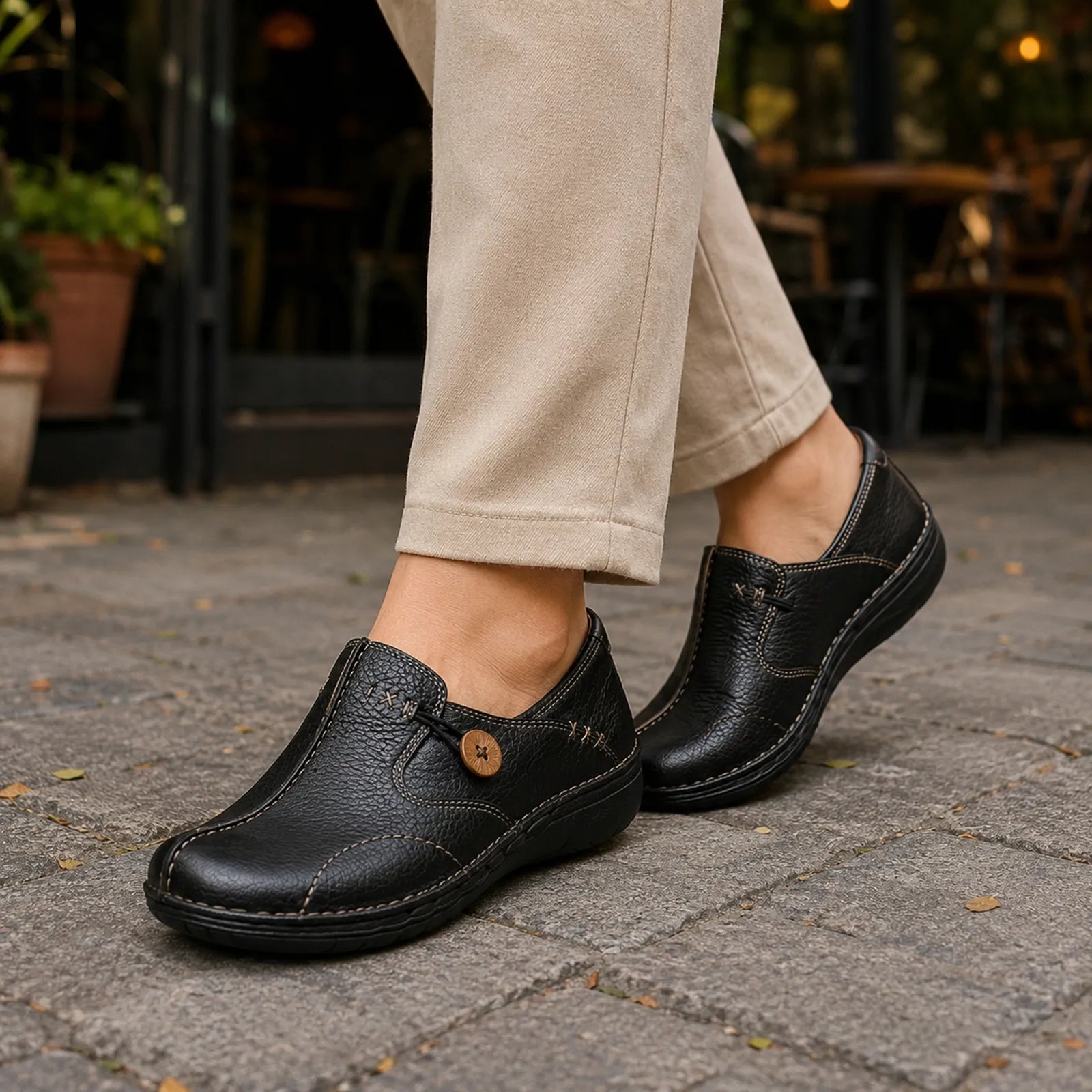 Black leather loafer worn with cropped pants, round button strap and low rubber sole