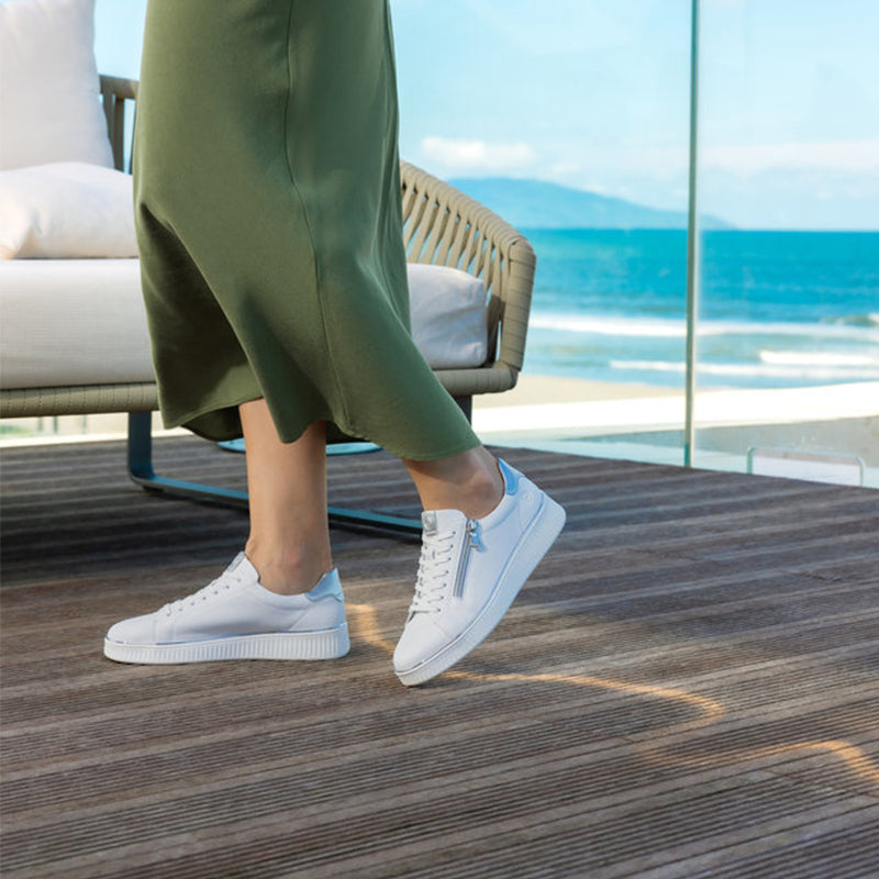 White sneakers with side zip and lace-up front, worn with green pants
