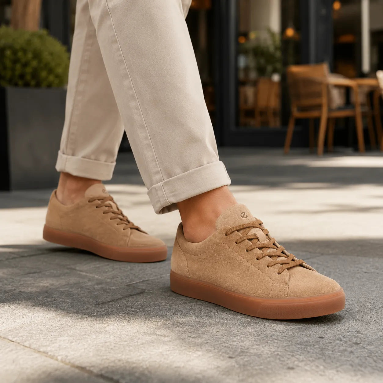 Men's suede lace-up sneakers worn with light pants, tan-brown uppers and gum sole