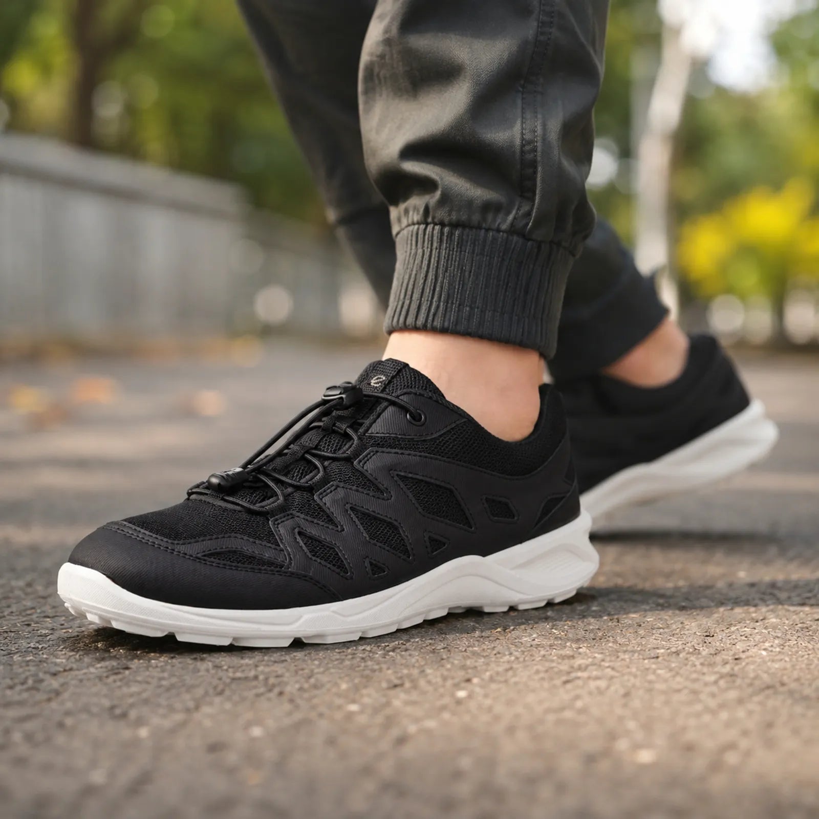 Women’s lightweight outdoor sneakers in black with white sole, worn on a street