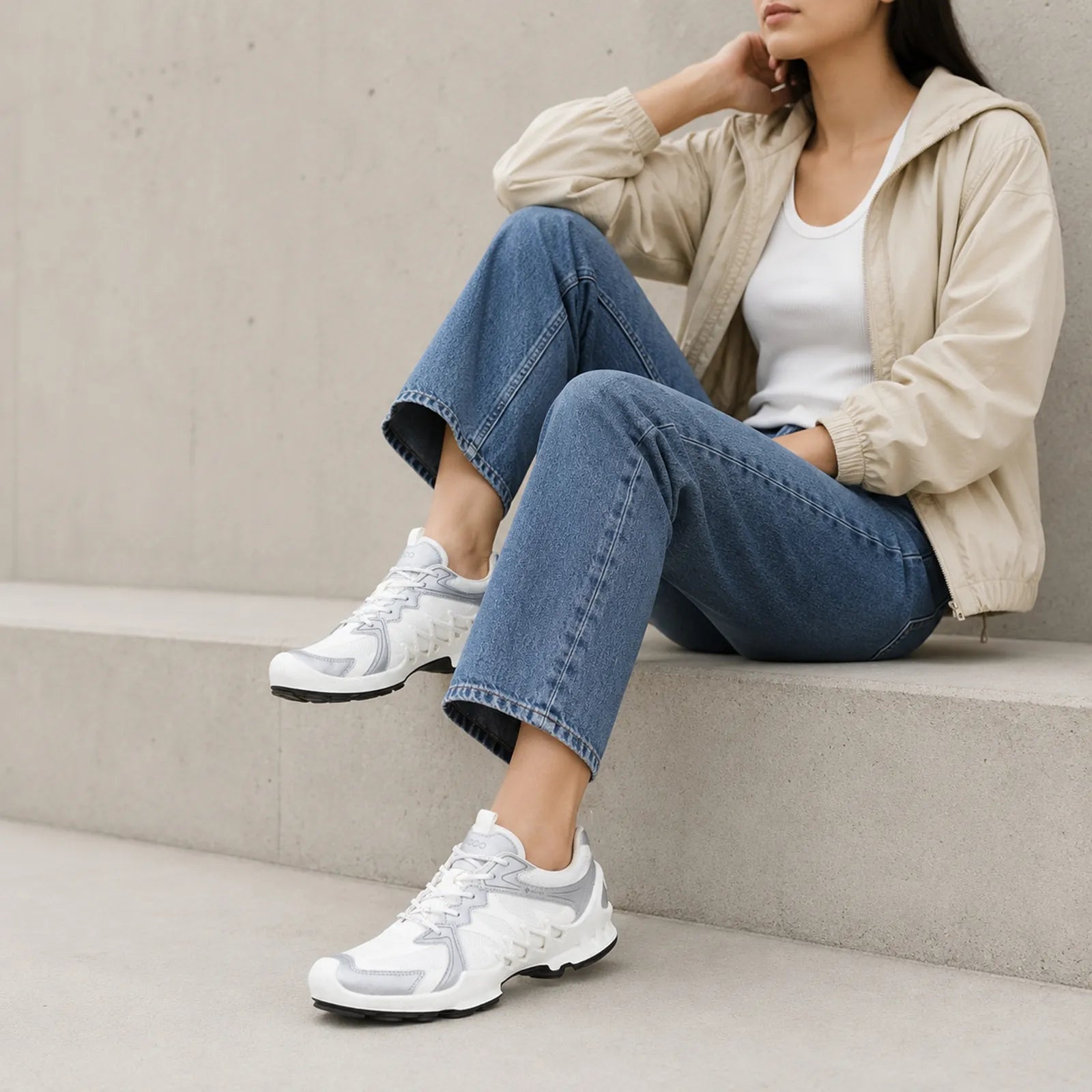 White lace-up sneakers with cushioned sole worn with jeans