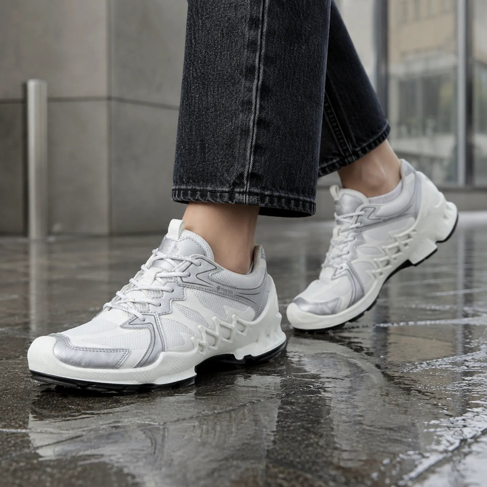 White lace-up sneakers with chunky sole and tread on wet pavement