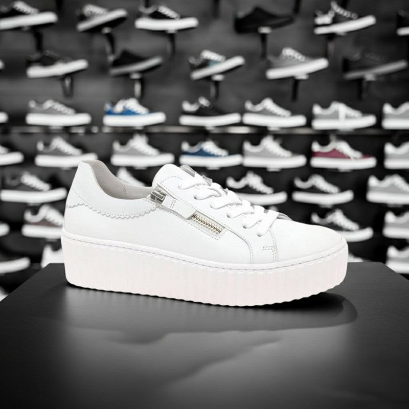 White leather platform sneakers with lace-up and side zipper, shown on a shoe display