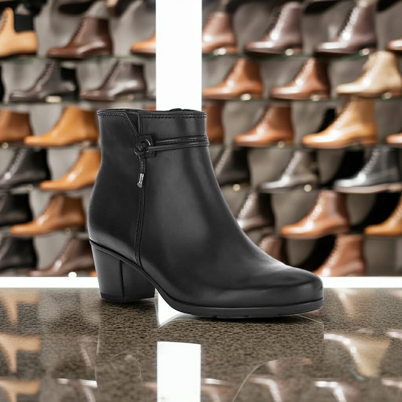 Women's black leather ankle boot on display, side zip, low block heel