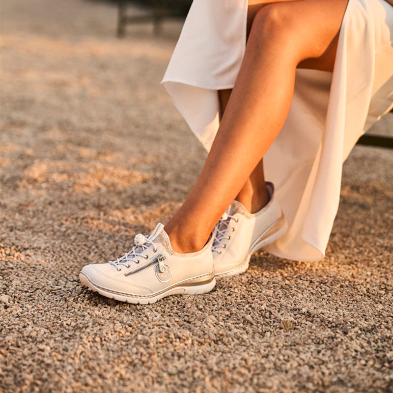 Women's white lace-up sneakers worn on feet