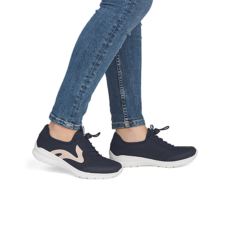 Navy sneakers worn with blue jeans, black laces, and white outsole
