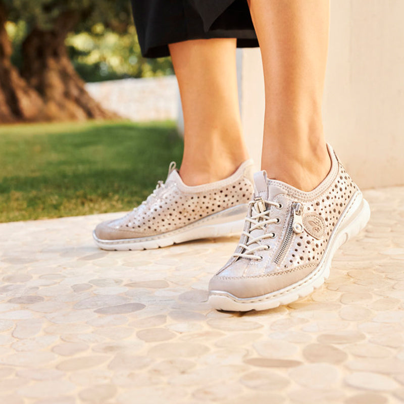 Women’s metallic lace-up sneakers on person, perforated upper and cushioned sole