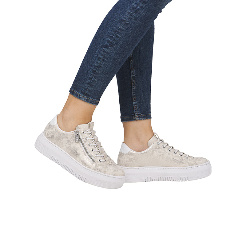 Beige low-top sneakers on legs with lace-up closure and textured light outsole