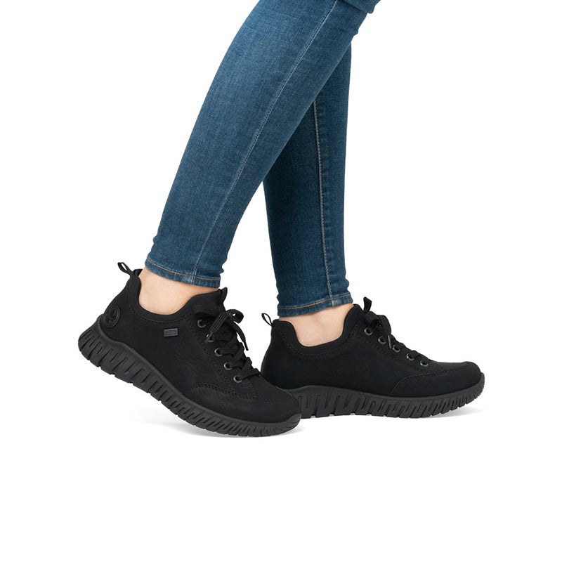 Black sneakers worn with blue denim jeans, lace-up style