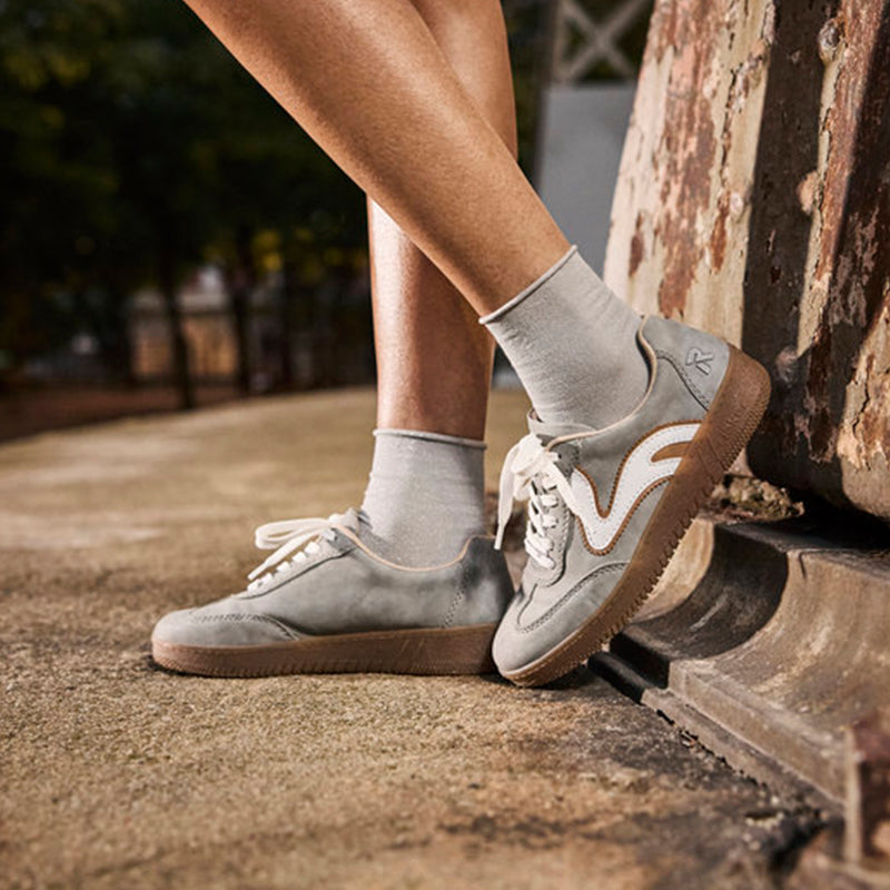Grey lace-up sneaker worn with white crew socks, tan rubber sole