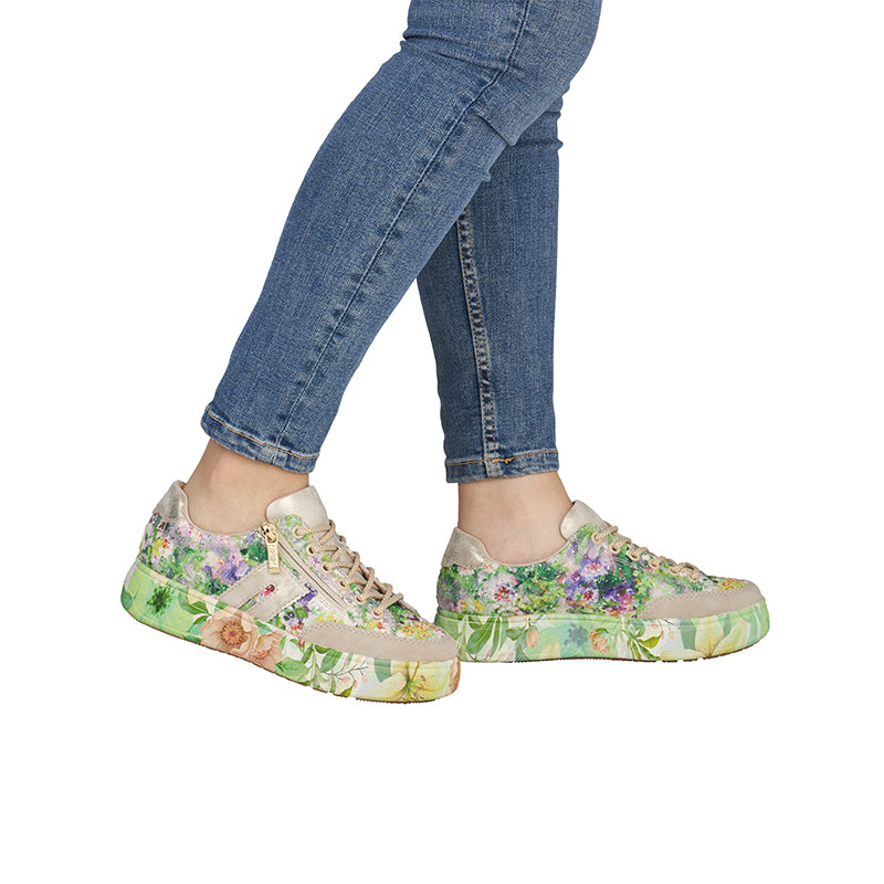 Women’s multicoloured floral sneakers on feet with denim jeans, lace-up design