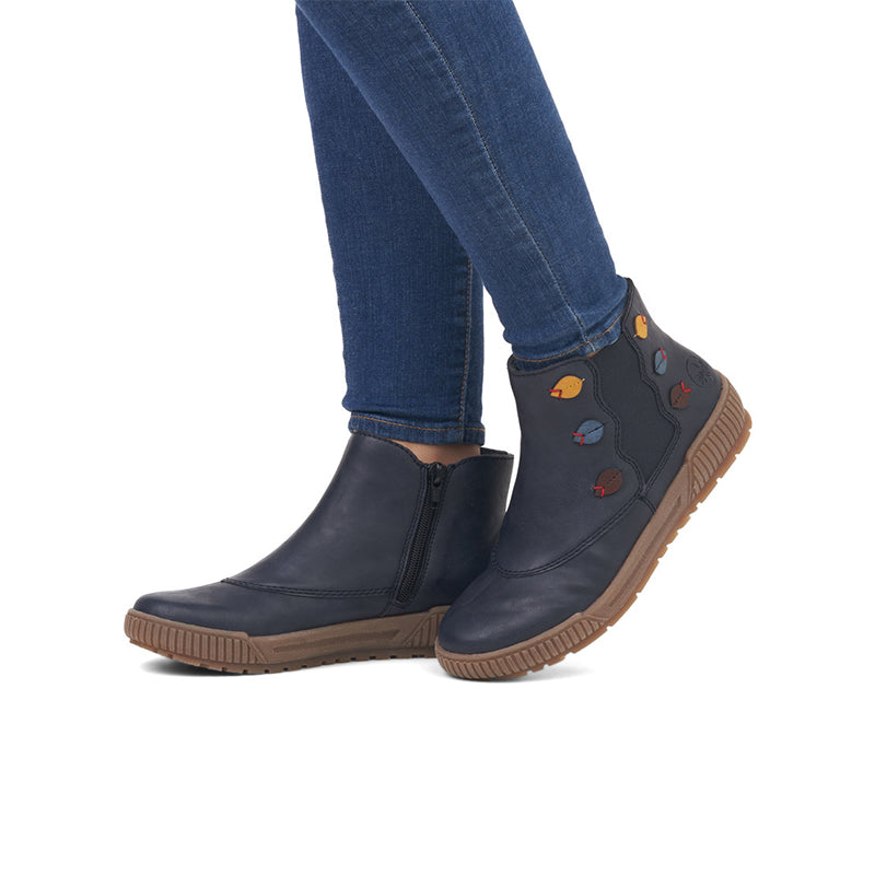 Women’s dark blue ankle boots with colorful patches, worn with blue jeans