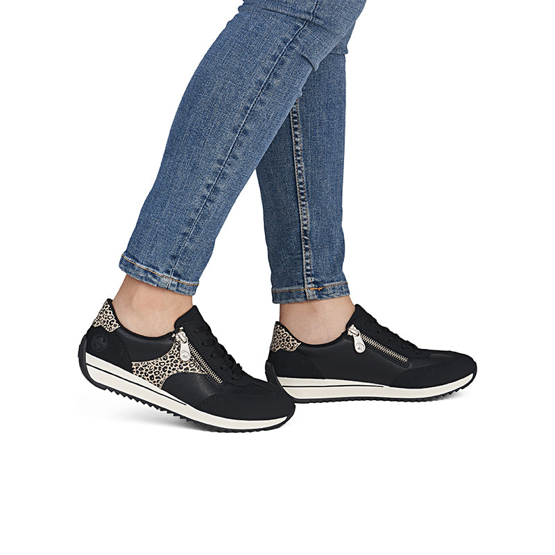 Women's black sneakers with leopard print side panels, worn with jeans