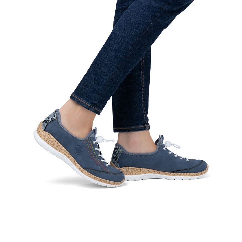 Women's blue slip-on sneakers on feet with jeans, white laces, cushioned outsole