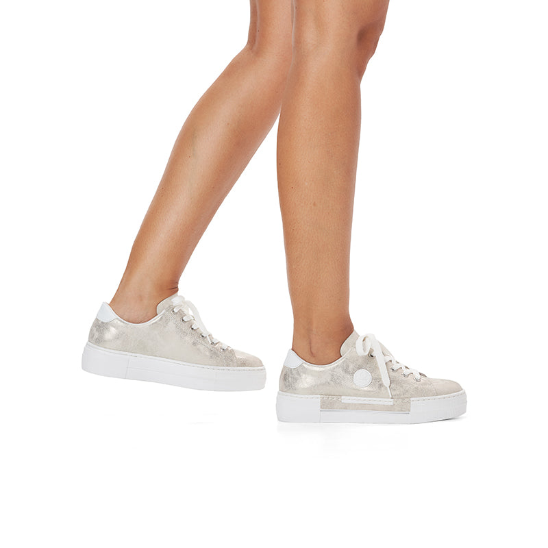 Pair of silver low-top lace sneakers on model with white rubber soles