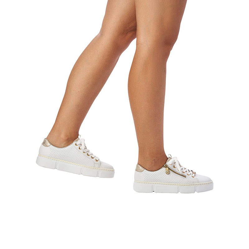 White low-top sneakers on legs with lace-up closure and thick platform soles