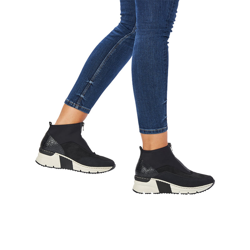 Black ankle boots on model feet, side zip and white chunky sole