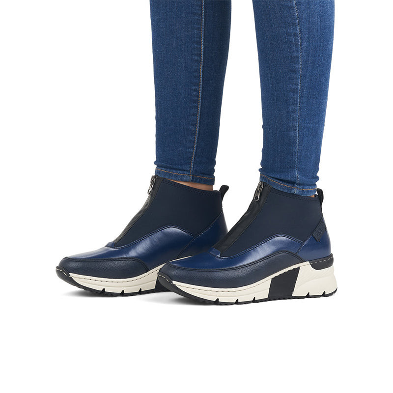 Blue ankle boots on model feet, side zip and white chunky sole