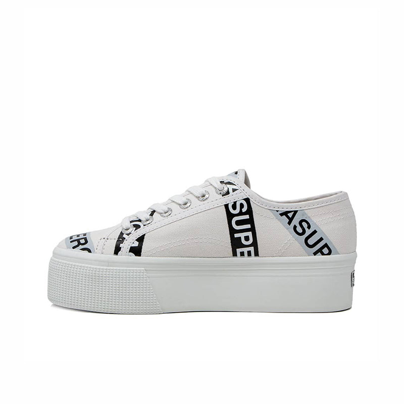 White canvas platform sneakers with lace-up front and branded side lettering tape detail