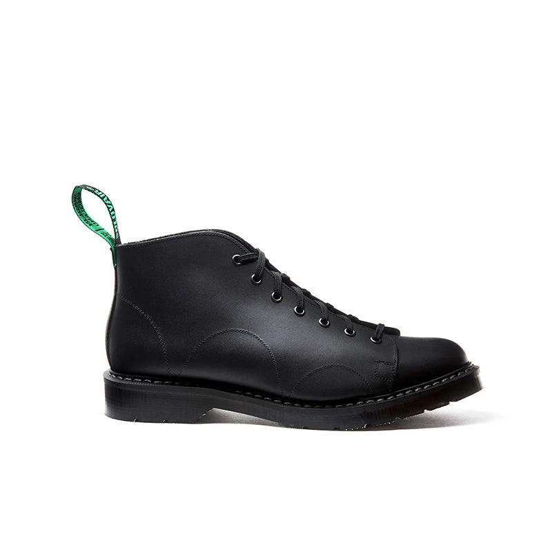 Black greasy leather 7-eye lace-up monkey boot with green pull loop, side view.