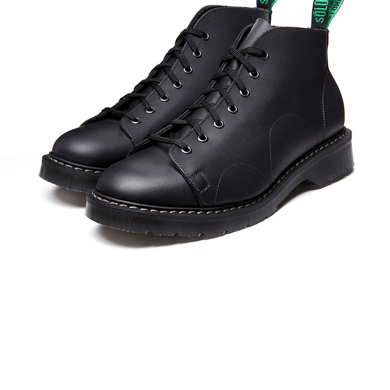 Black greasy leather 7-eye lace-up monkey boots, angled front view.