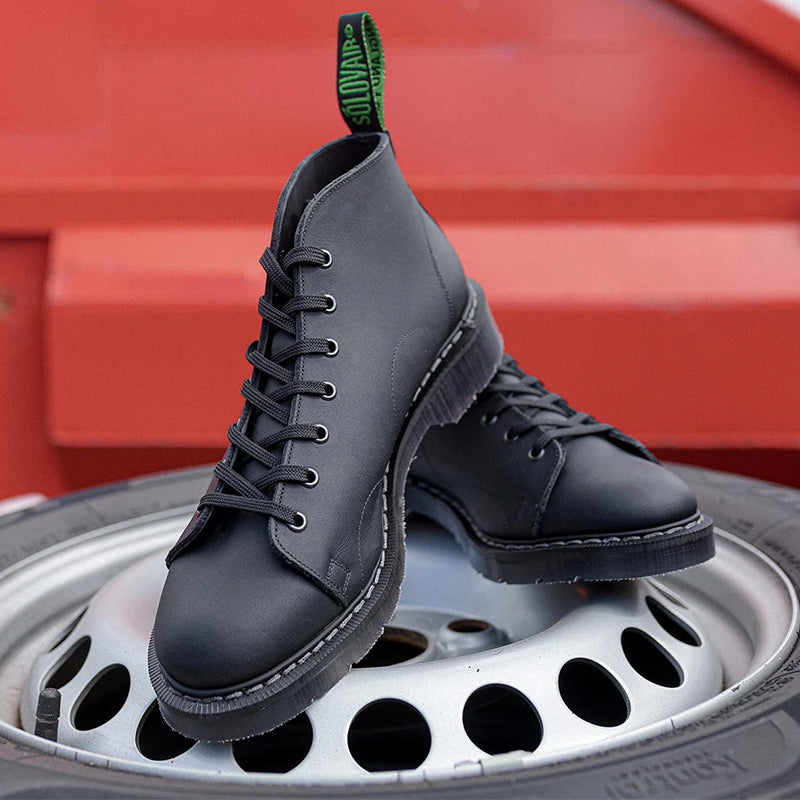 Black leather lace-up monkey boots, side view with green pull tab.