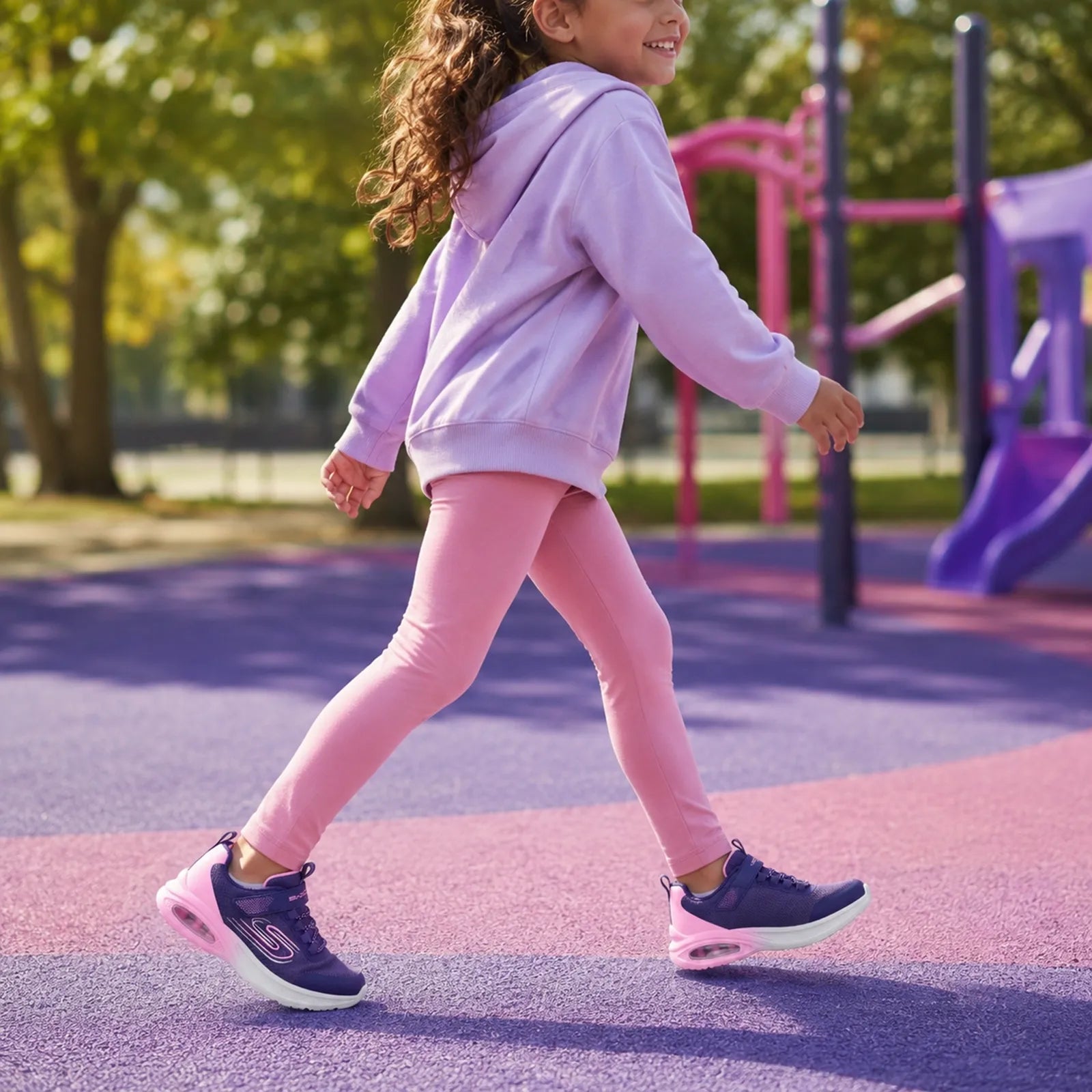 Girls' walking sneakers with navy uppers and pink accents on a playground