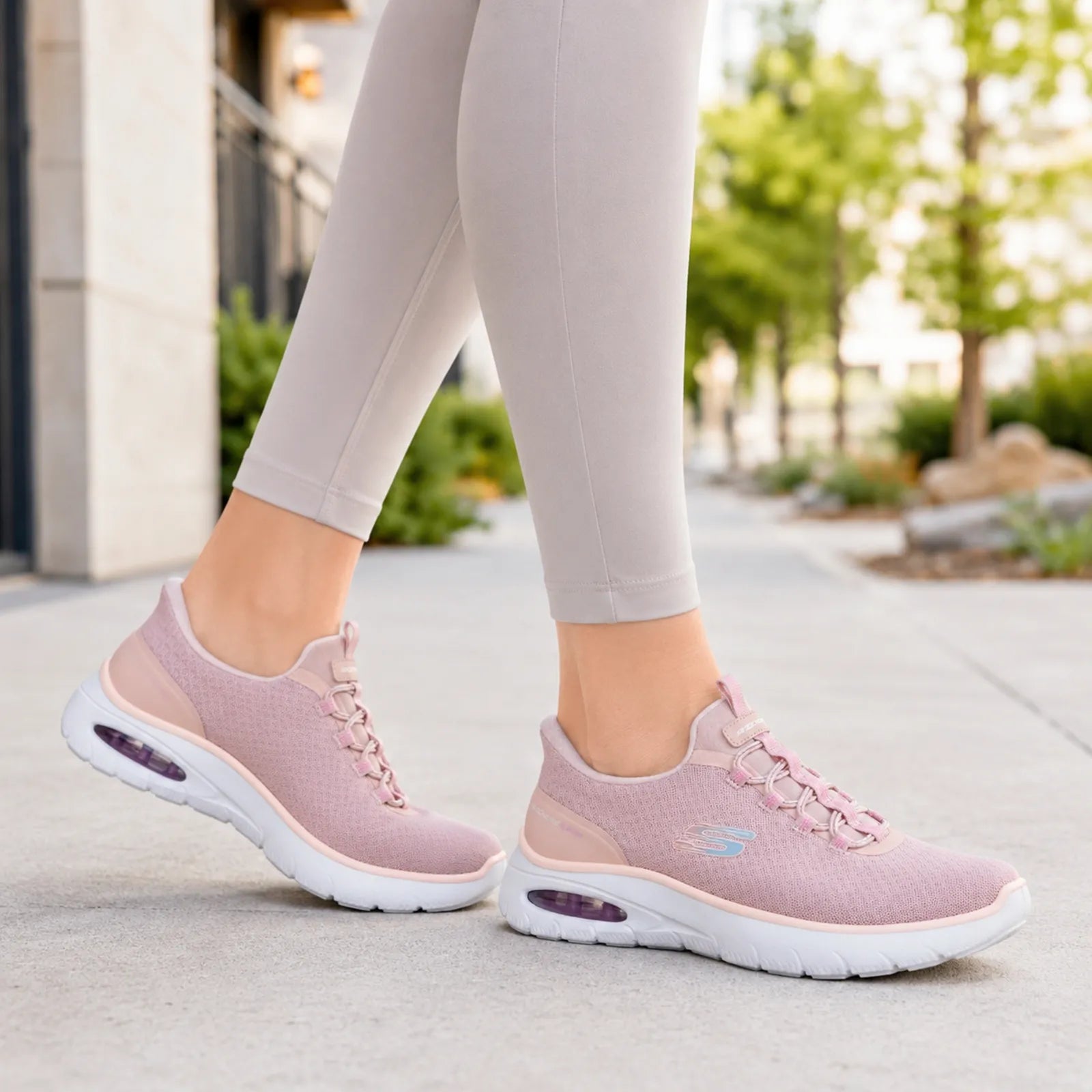 Pink Skechers slip-on sneakers on feet with lace-up front and air-cushioned sole