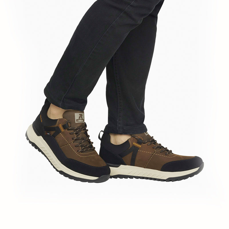 Men's brown and black lace-up sneakers worn with dark pants