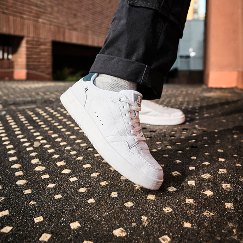 White leather lace-up sneaker on foot with navy heel collar