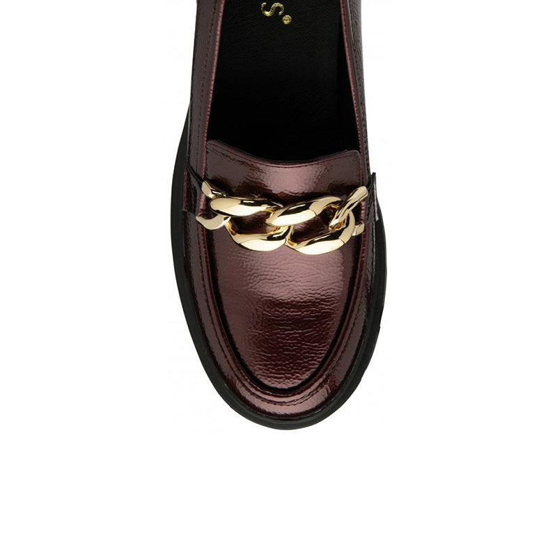Close-up of bordo patent loafer with gold chain accent across the vamp