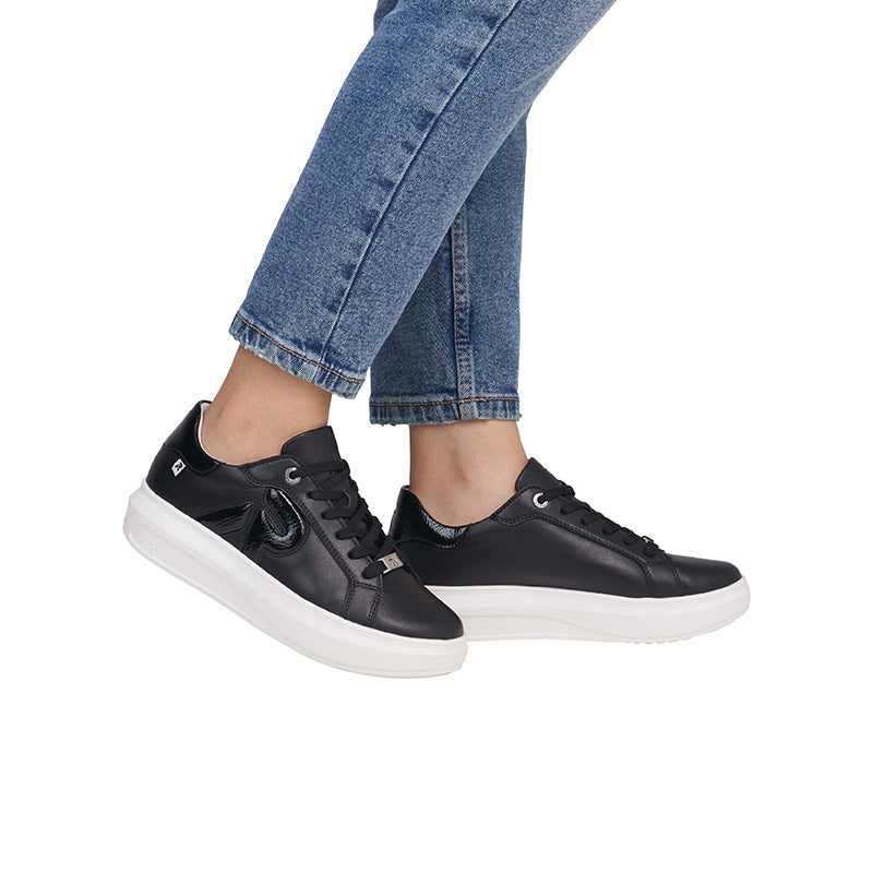 Black leather lace-up sneakers on model with cropped jeans