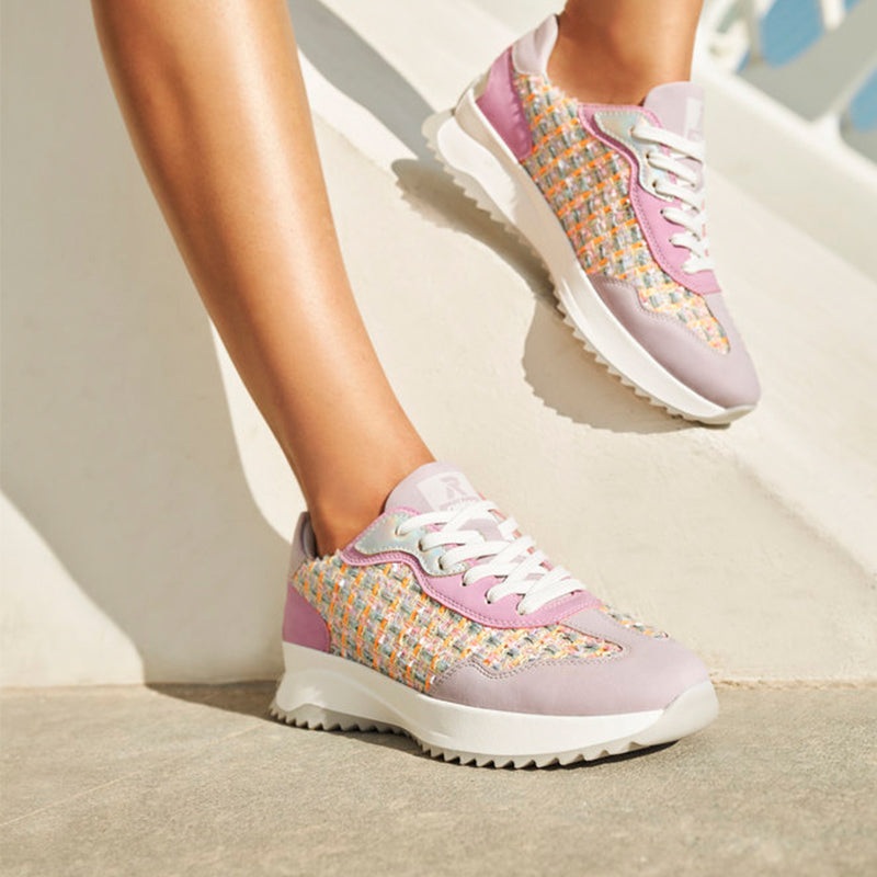 Women’s trainers on legs: lavender woven uppers, white laces, chunky white sole