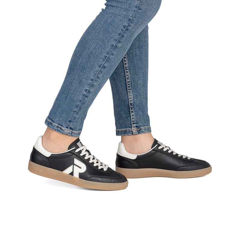 Black and white lace-up sneakers with gum sole, worn with blue jeans