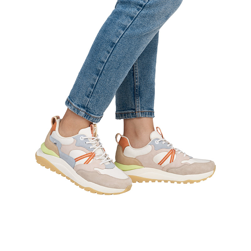 Women’s sneakers with multicolor uppers, orange laces, lime-green sole, worn with blue jeans